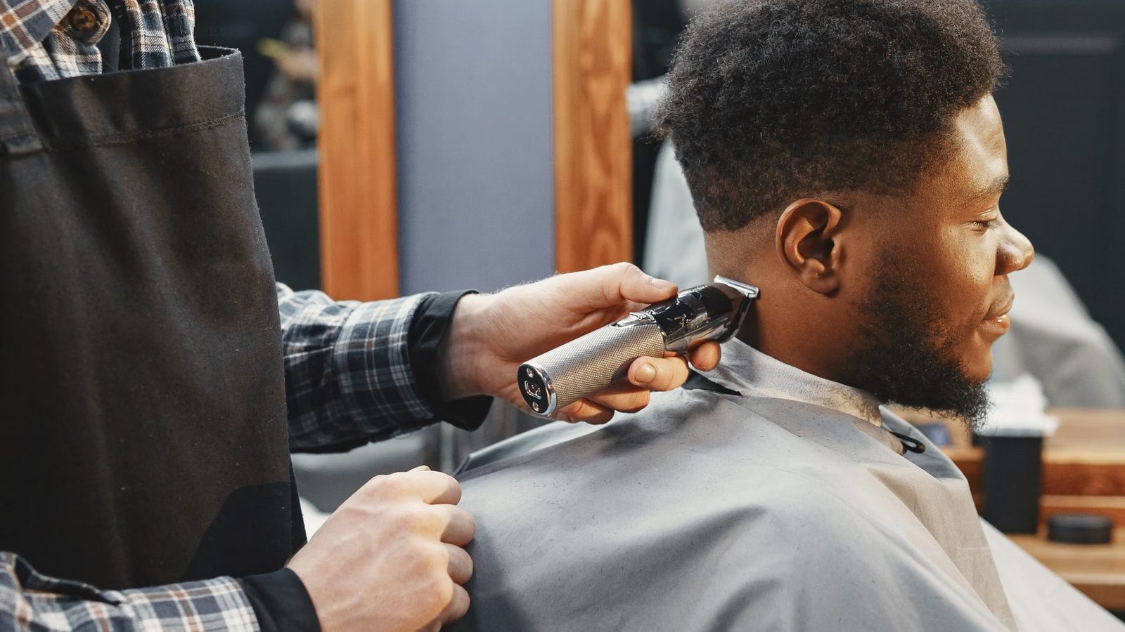 Fryzjer strzyże klienta w barber shopie