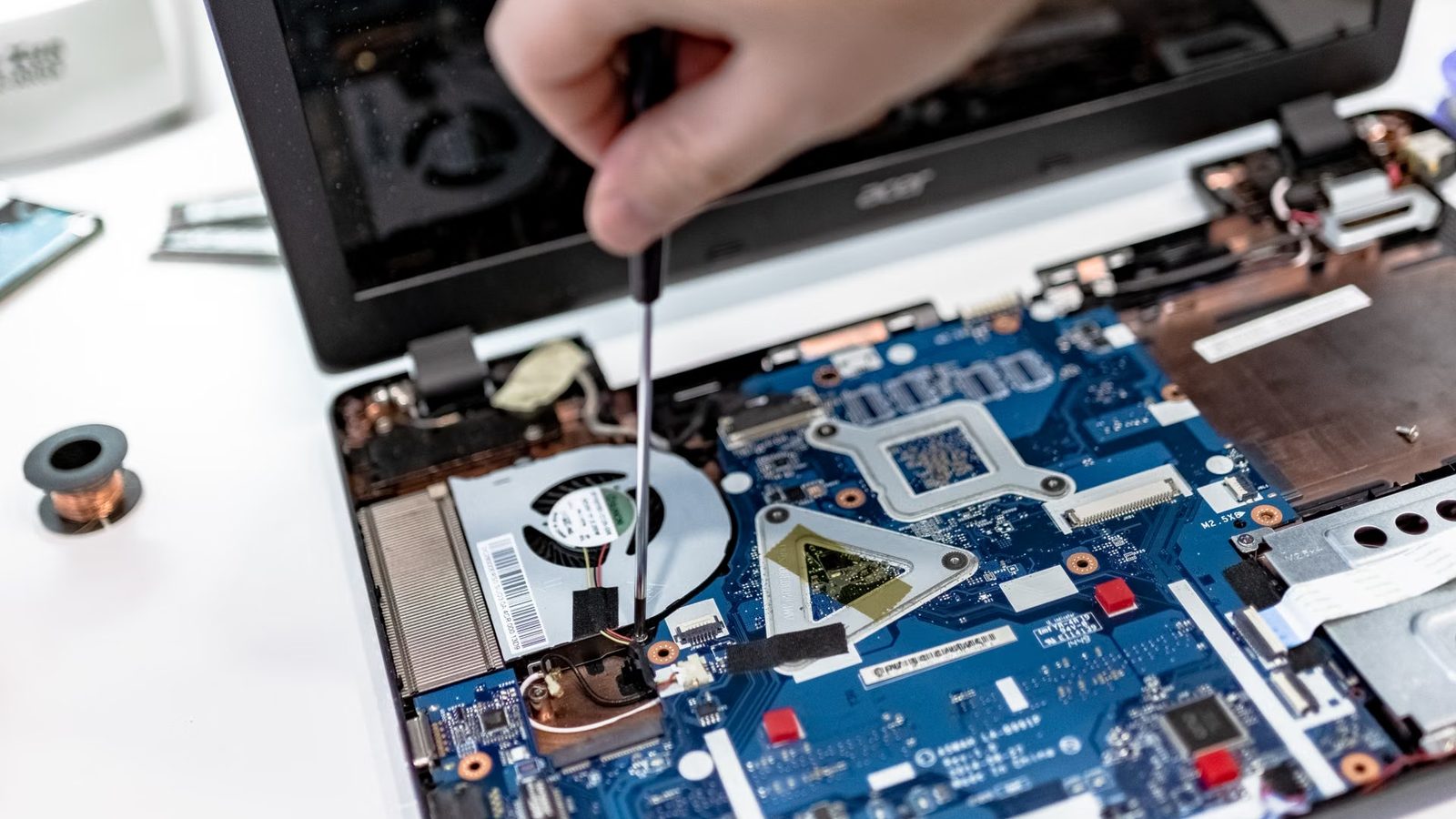 Technik odkręca śrubokrętem elementy w otwartym laptopie