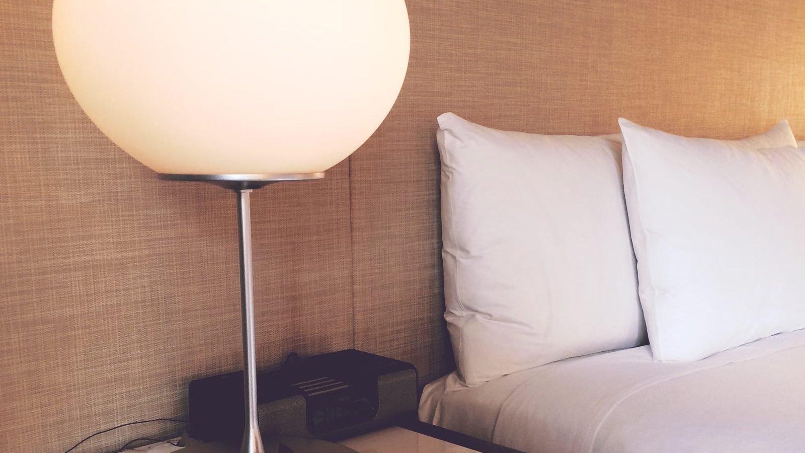 Lampka nocna i łóżko w pokoju hotelowym