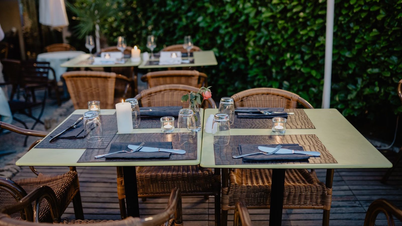 Nakryte stoliki z wiklinowymi krzesłami w ogródku restauracji wieczorem