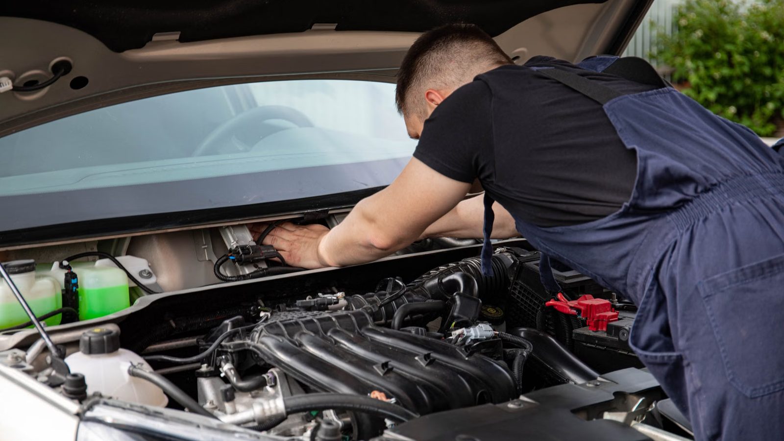 Mechanik sprawdza silnik pod otwartą maską samochodu