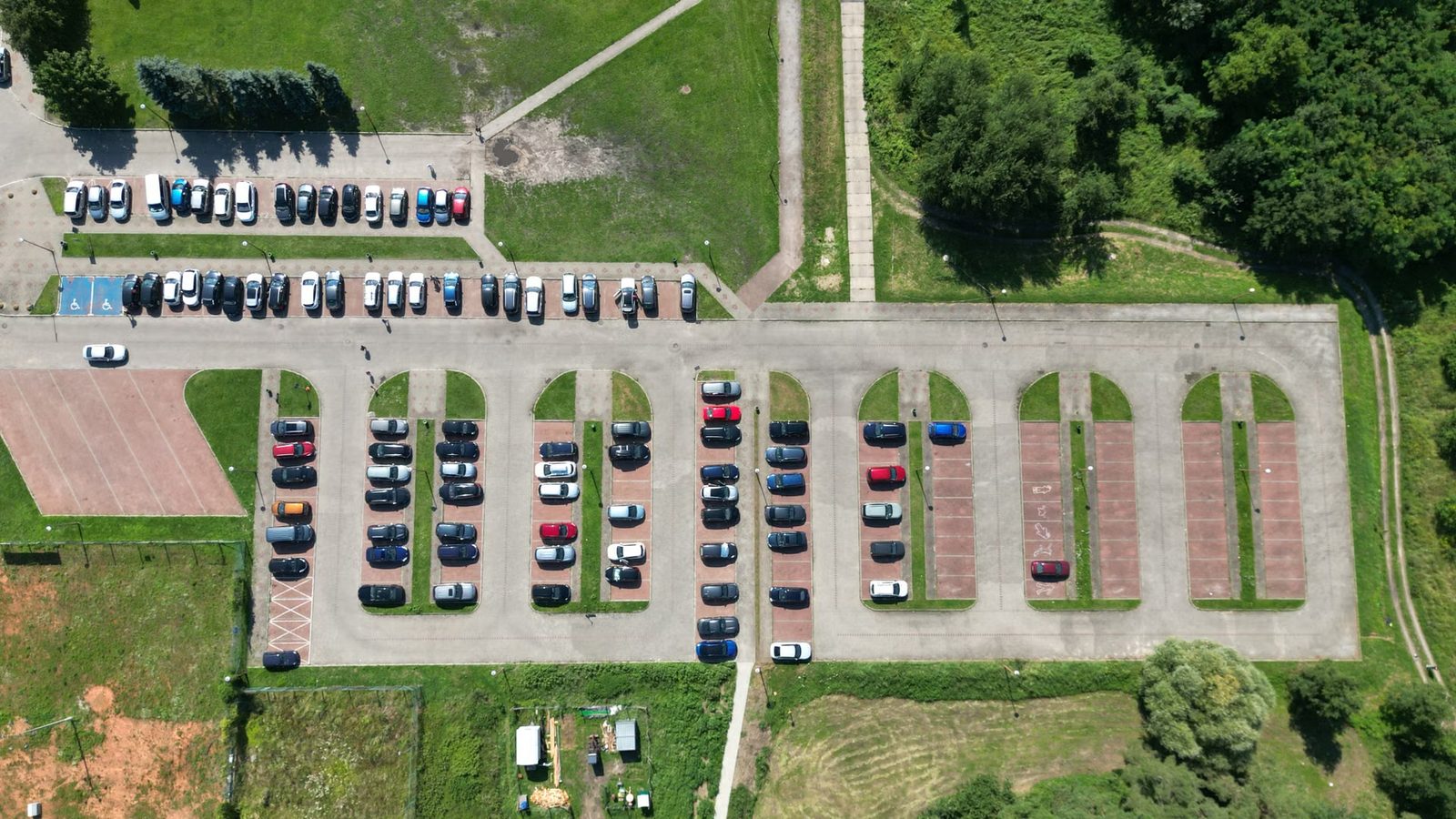 Parking z rzędami zaparkowanych samochodów i pustymi miejscami widziany z góry
