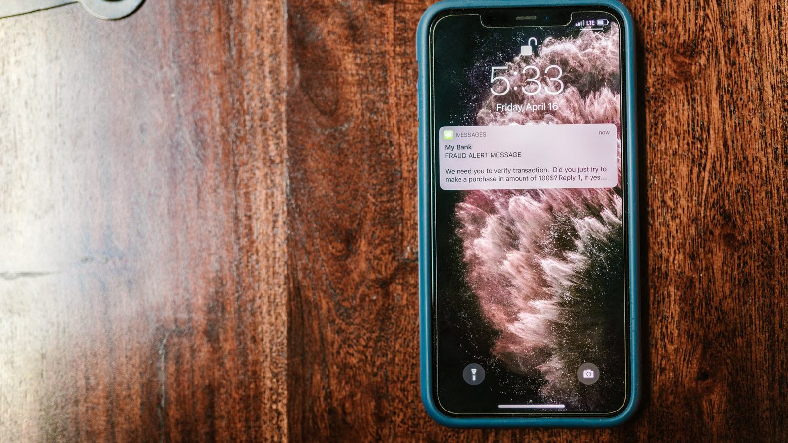 Smartfon z powiadomieniem na ekranie blokady leży na drewnianym stole