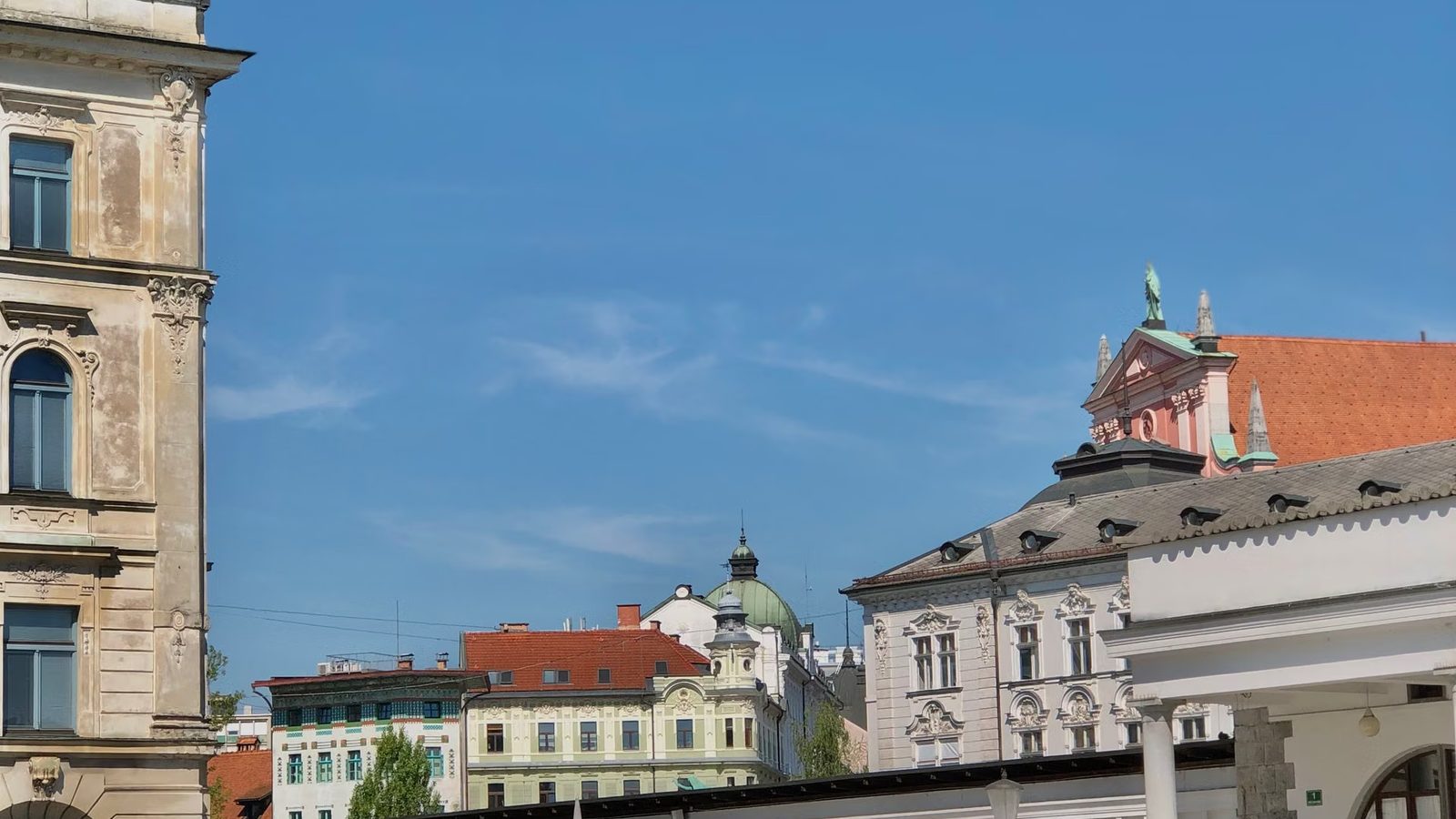 Zabytkowe kamienice i różowa fasada kościoła pod błękitnym niebem
