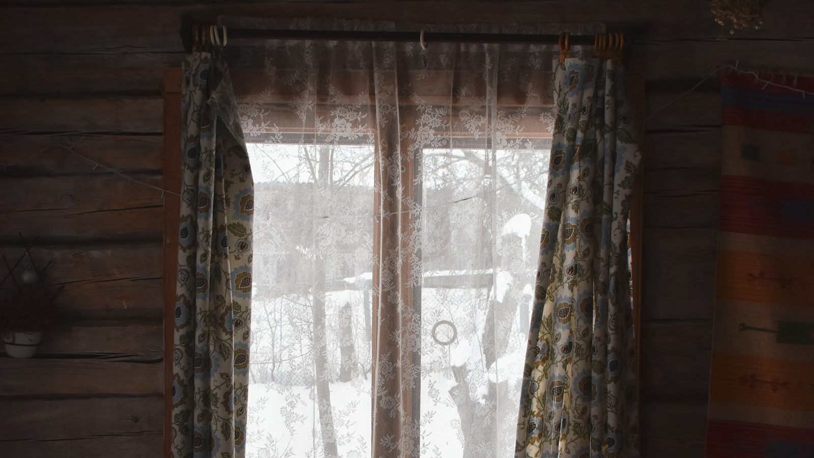 Okno drewnianego domku z widokiem na śnieg