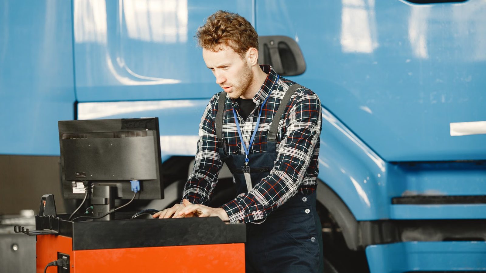 Mechanik przy komputerze diagnostycznym obok ciężarówki