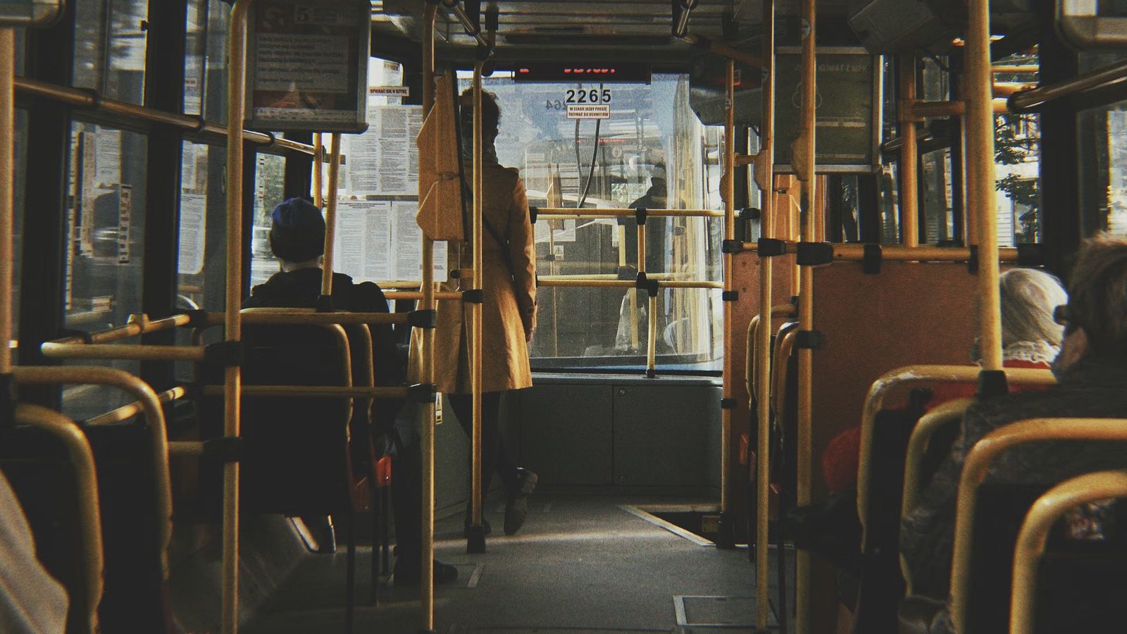 Pasażerowie w autobusie miejskim przy żółtych poręczach