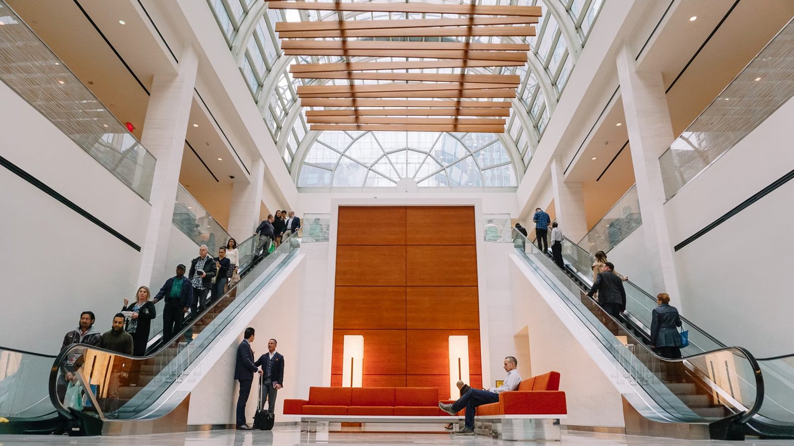 Ludzie na schodach ruchomych w przeszklonym atrium biurowca