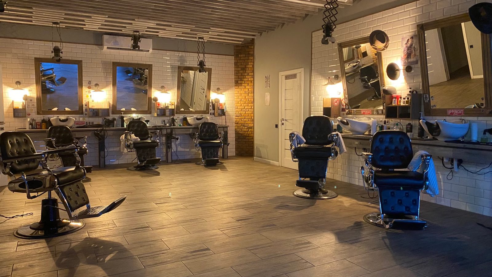 Wnętrze zakładu fryzjerskiego z fotelami barberskimi i lustrami