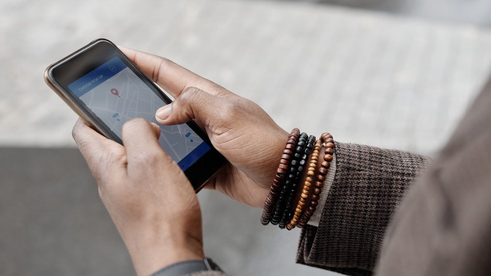 Dłonie trzymają telefon z otwartą mapą i pinezką