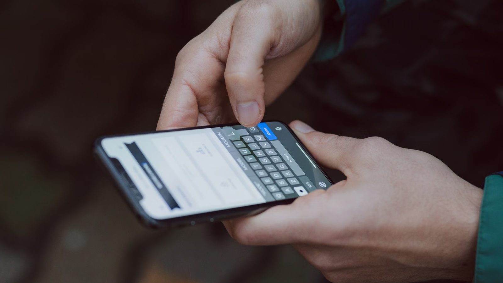 Dłonie wpisują wiadomość na klawiaturze smartfona