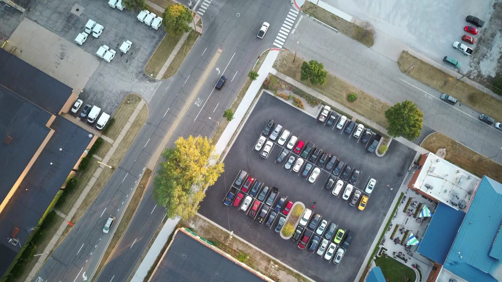 Widok z drona na parking pełen samochodów przy ulicy i budynkach