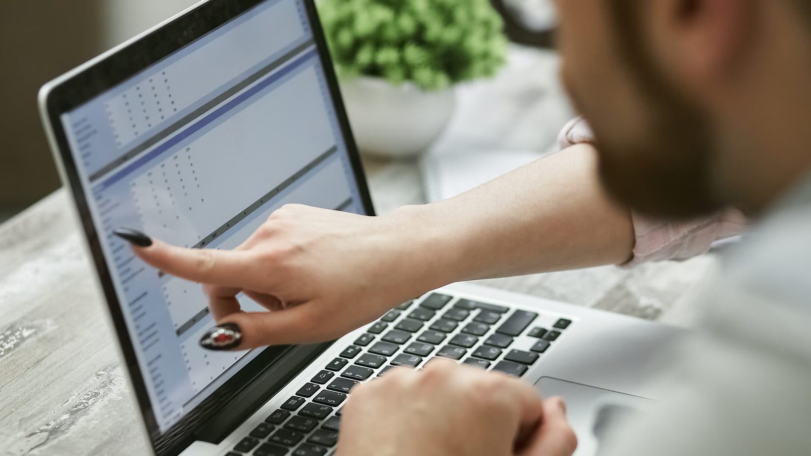 Statystyki na ekranie laptopa i dłonie na klawiaturze