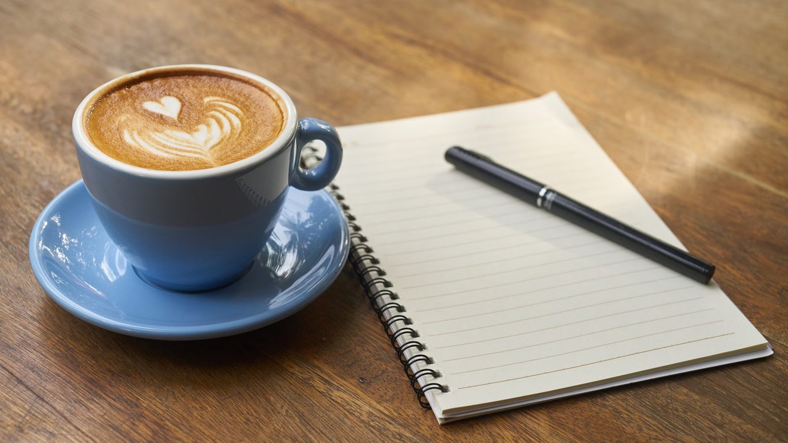 Kubek kawy i notes na porannym biurku