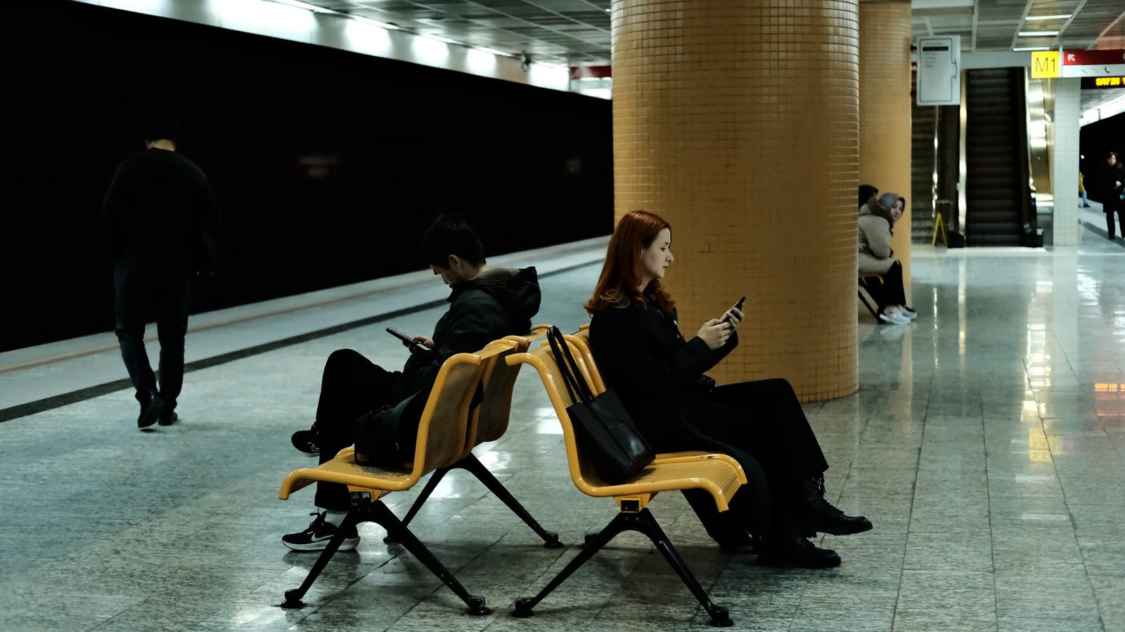 Pasażerowie z telefonami na peronie rano