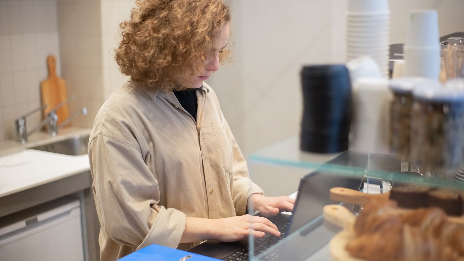 Kobieta przy laptopie za ladą małego sklepu