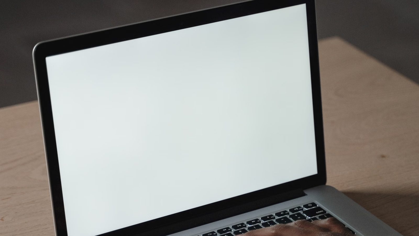 Dłonie na klawiaturze laptopa obok rośliny