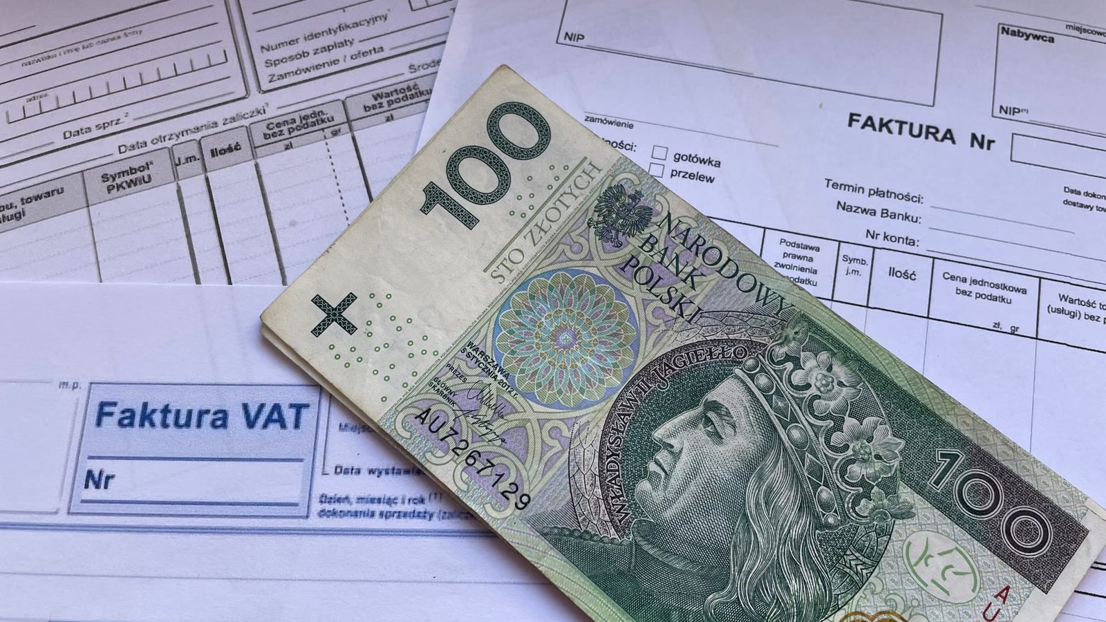 Faktura VAT i banknot stuzłotowy na biurku