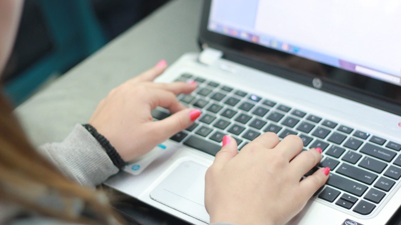 Dłonie na klawiaturze laptopa przy pracy nad projektem